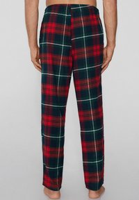 Czerwono-zielone flanelowe spodnie od piżamy w kratę, z elastycznym pasem i luźnym krojem, charakteryzujące się miękką fakturą i prostym fasonem.