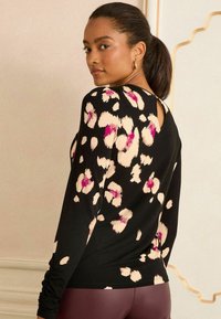 Melna garām piedurknēm pierešanas krekls ar leoparda rakstu krēmkrāsā un rozā. Aizmugurē ir atvēruma detaļa. Mīksts audums ar šauru piegriezumu.