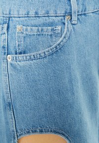 Ljusblå denimshorts med fransig fåll, som har en bakficka och silverfärgade beslag. Tyget har en klassisk denimstruktur.