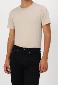 Beige T-shirt met korte mouwen en een ronde hals, gemaakt van zachte stof, gecombineerd met zwarte spijkerbroek met een klassieke vijf-pocketontwerp.