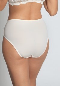 Beige hochgeschnittene Pantys aus glattem Stoff, mit einem gewellten Bund und nahtlosen Kanten für Komfort und eine saubere Passform.
