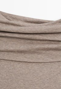 Tessuto beige e morbido con una superficie texture, che presenta pieghe drappeggiate. Caratterizzato da un motivo di maglia sottile e uniforme su tutto il materiale.