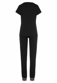 Schwarzes Zweiteiler-Outfit mit einem kurzärmeligen Oberteil und schmal zulaufenden Hosen mit gestreiften Akzenten an den Knöchelbündchen. Weicher, glatter Stoff.