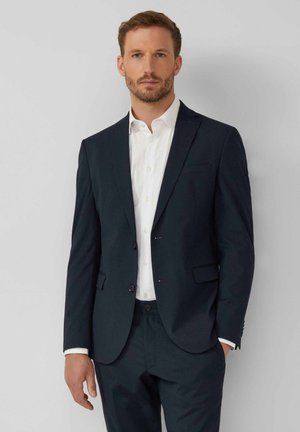 Navy suit made of smooth fabric, featuring a single-breasted jacket with notch lapels and two front pockets, paired with a white shirt.