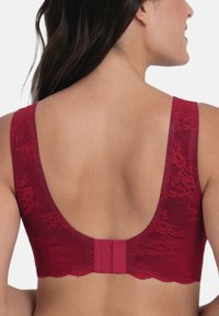 Czerwona koronkowa biustonosz z głębokim dekoltem z tyłu, szerokimi ramiączkami i trójhakowym zapięciem dla wsparcia. Miękki, teksturowany wzór kwiatowy w całej konstrukcji.