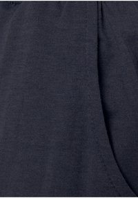 Tejido de algodón azul marino con una textura suave y un detalle ligeramente acanalado a lo largo de los bordes. Vista en primer plano que muestra las costuras y los pliegues.