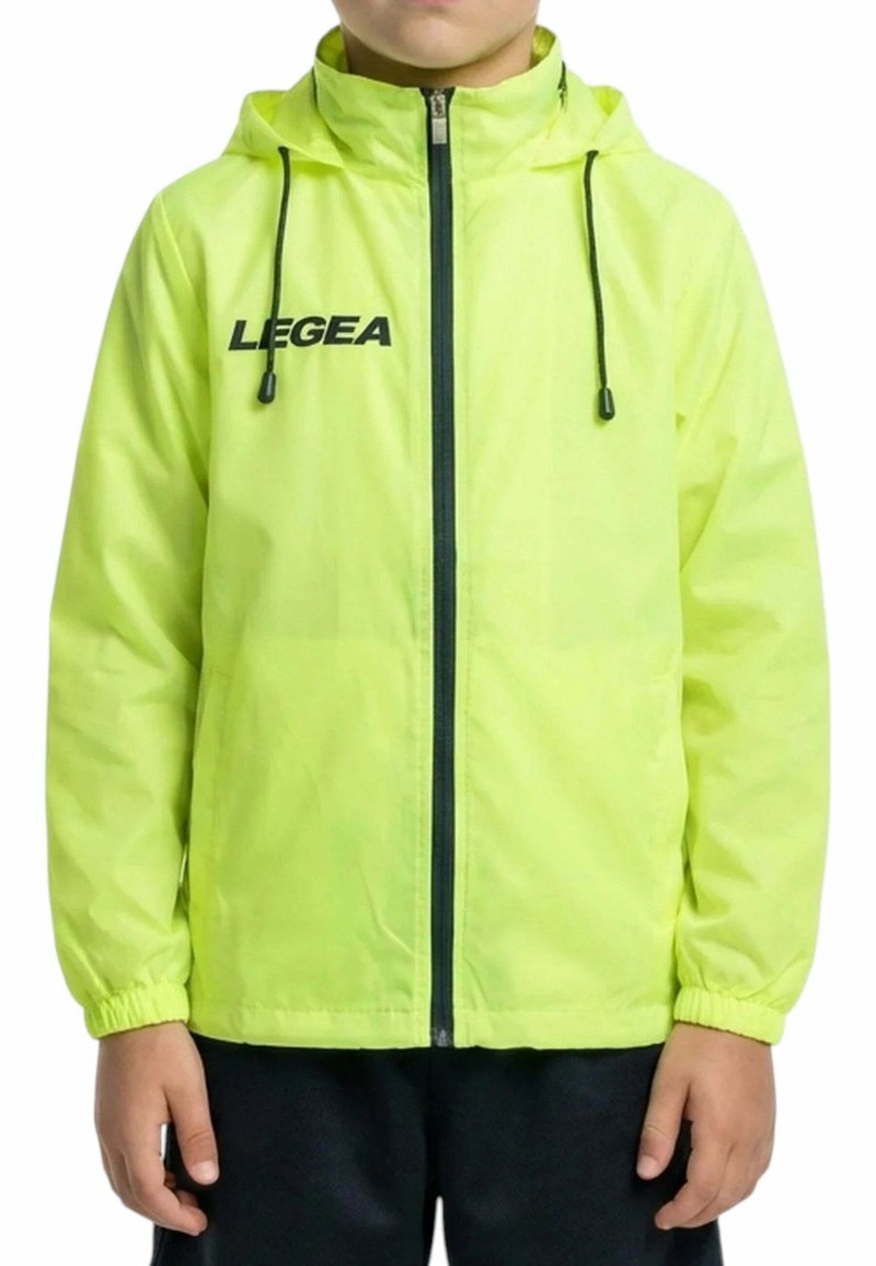 Enfant portant une veste à capuche jaune vif avec une fermeture éclair noire et des cordons, et le logo "LEGEA" sur le côté gauche de la poitrine, sur fond blanc.