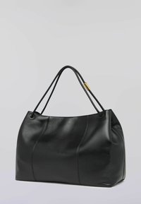 Svart läderhandväska med slät textur, rundad form, dubbla handtag och subtila sömdetaljer. Har en guldfärgad metallaccent.