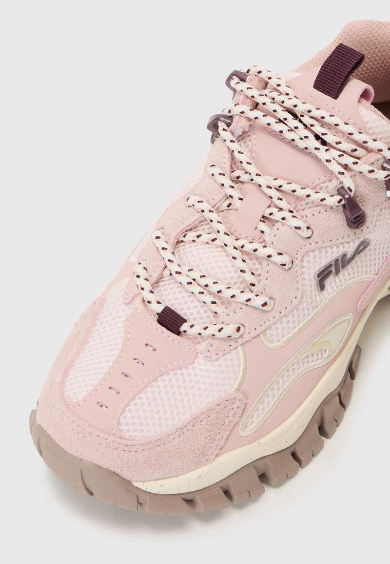 Sneaker rosa con materiale in rete e suede, dettagli testurizzati, chiusura con lacci e accenti crema a contrasto. Suola in gomma spessa.