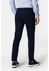 Granatowe, dopasowane spodnie wykonane z mieszanki bawełny, z tylnymi kieszeniami i gładką fakturą. W zestawie z czarno-białymi Sneakersami.