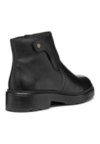 Bottes de cheville en cuir noir avec une texture lisse, talon plat, ouverture latérale et un accent en métal doré. Présentent une semelle en caoutchouc durable.