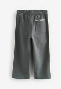 Temno sive trenirka z zadnjim žepom, elastičnim pasom in kontrastnimi svetlimi stranskimi črtami. Na zadnji strani je napis "ALLSAINTS" v beli barvi.