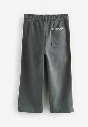 Tmavomodrošedé tepláky s zadným vreckom, elastickým pásom a kontrastnými svetlými bočnými pruhmi. Na zadnej strane je biely nápis "ALLSAINTS".