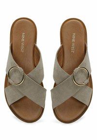 Sandalias deslizantes de ante gris con tiras cruzadas y un acento circular dorado. Plantilla y suela texturizada marrón para un agarre y comodidad óptimos.