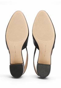 Chaussures à talons hauts noires avec une tige en cuir lisse, des côtés ouverts et une semelle extérieure en caoutchouc texturé. Marquées "TOMMY HILFIGER" sur la semelle.