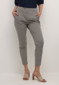 Mönstrade tapered byxor med geometriskt mönster, stretchigt tyg, sidofickor och midjeband i marinblått. Kombineras med neutrala blockklack-mules.