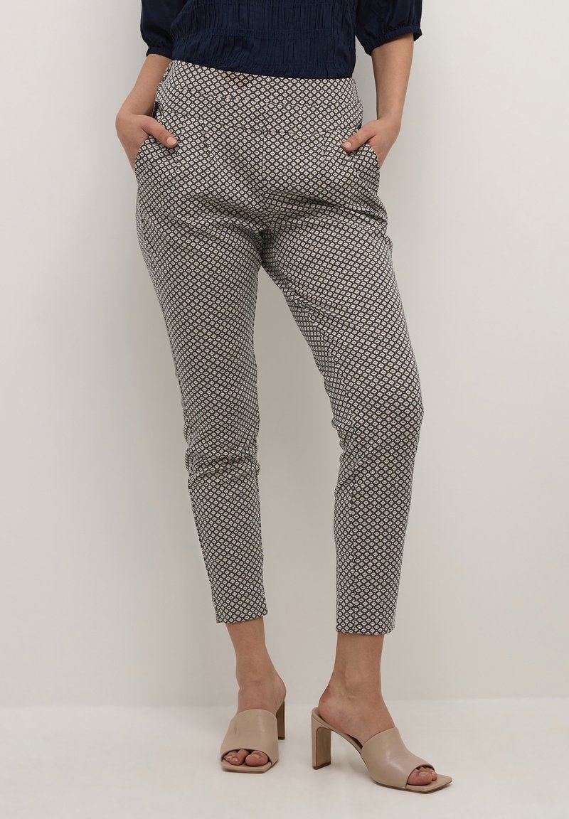 Mönstrade tapered byxor med geometriskt mönster, stretchigt tyg, sidofickor och midjeband i marinblått. Kombineras med neutrala blockklack-mules.