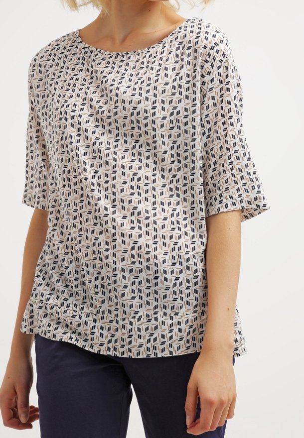 Blusa a maniche corte in tessuto leggero, con un motivo geometrico blu navy, beige e crema. Collo rotondo con vestibilità comoda.