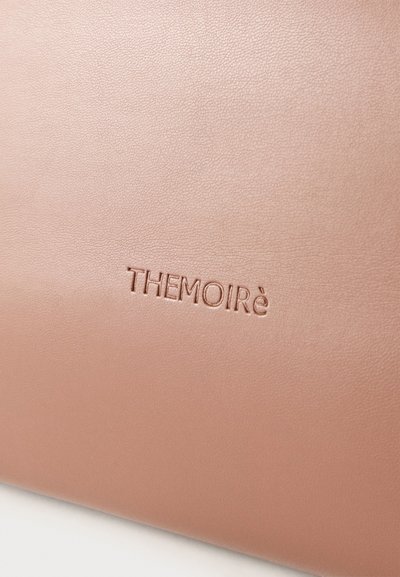 Λεία επιφάνεια από ροζ δέρμα με την λέξη "THEMOIRè" ανάγλυφη στο κέντρο.