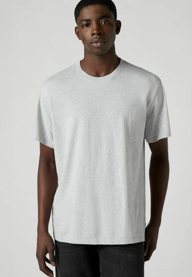 Hellgraues T-Shirt mit kurzen Ärmeln aus weichem Stoff, mit Rundhalsausschnitt und geradem Schnitt. Es bietet eine lockere Passform und minimalistische Nahtakzente.