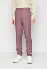 Heledad lilla tekstuuriga püksid, slim fit lõikega, nuppude sulgemisega ja taskutega, koos valgete spordikingadega.