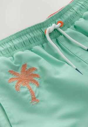 Mintgrüne Badeshorts mit einem elastischen Bund, ausgestattet mit einer weißen Zugkordel und einem gestickten orangen Palmen-Design.
