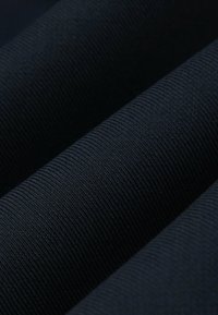 Czarna tkanina z teksturowaną, prążkowaną powierzchnią o delikatnym połysku, złożona w warstwowe sekcje, które ukazują jej gładki, trwały materiał.