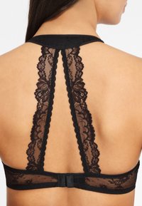 Černá krajková bralette s květinovým vzorem, designem racerback a zapínáním na háček a oko vzadu. Měkká, průhledná textura.
