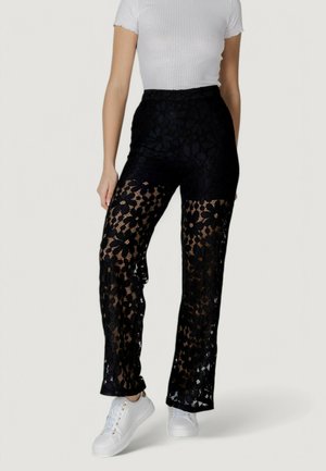 I pantaloni neri in pizzo presentano un motivo floreale, un tessuto semitrasparente, una vita alta e una vestibilità slim. Indossati con sneakers bianche per creare un contrasto.