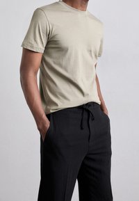 Jasno beżowy t-shirt z krótkim rękawem wykonany z miękkiej bawełny, połączony z czarnymi spodniami na sznurki, w luźnym kroju, z bocznymi kieszeniami.