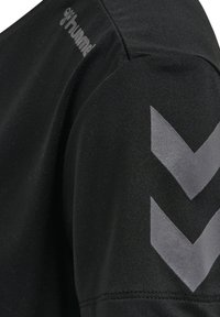 Schwarzes Sportshirt aus weichem Stoff mit kurzen Ärmeln und einem auffälligen grauen Zickzackmuster auf dem Ärmel, versehen mit Detail-Logo.