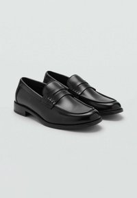 Mocasines de cuero negro con un acabado suave, que presentan un diseño de tira elevada en el empeine y un tacón bajo en bloque. Forma de punta redonda.