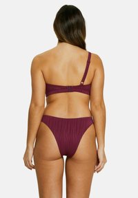 Ensemble bikini en bordeaux foncé, comprenant un haut asymétrique avec une bandoulière réglable et un tissu texturé, associé à un bas taille haute.