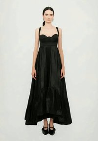 Črna maksi obleka z oprijetim korzetom in širokim krilom. Ima teksturirano tkanino, tanke naramnice in valovit ovratnik.