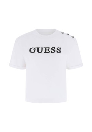 T-shirt bianca a maniche corte con taglio corto, con scritta nera "GUESS" sul davanti e tre bottoni argentati sulla spalla sinistra.