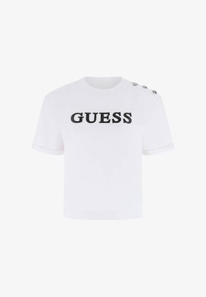 Camiseta blanca de manga corta y corte corto con texto negro "GUESS" en el frente y tres botones plateados en el hombro izquierdo.