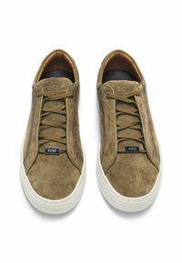 Sneaker in suede verde con suole in gomma bianca, dotati di punte arrotondate, lacci e un accentuato logo sul lato. Finitura morbida e testurizzata.