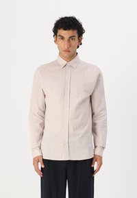 Camicia a maniche lunghe di colore rosa chiaro con un motivo testurizzato e colletto a punta, dotata di bottoni frontali e una silhouette aderente.