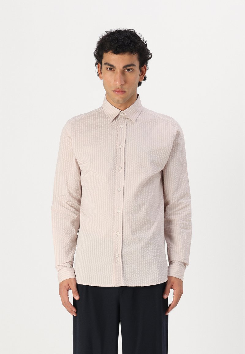 Camicia a maniche lunghe di colore rosa chiaro con un motivo testurizzato e colletto a punta, dotata di bottoni frontali e una silhouette aderente.