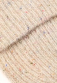 Béžová pletená vlnená tkanina s textúrovaným povrchom, ktorá obsahuje farebné bodky v červenej, modrej a zelenej farbe roztrúsené po celej látke.