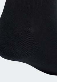 Black sock with a smooth, textured knit. Features a reinforced toe and heel, subtly integrating comfort with durability in design.