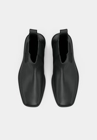 Melnas Čelsijas zābakus, kas izgatavoti no gludas ādas, ar elegantu dizainu, elastīgām sānu paneļiem un taisnstūra formas purngalu.