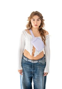 Lilac crossbody taška s kulatým tvarem a měkkou látkou. Obsahuje jeden popruh a embosované logo značky. Nosená přes zkrácený svetr a volné džíny.