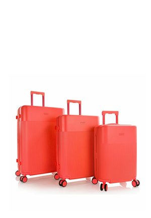 Tres maletas rígidas rojas de diferentes tamaños con asas extensibles y cuatro ruedas dobles giratorias cada una, colocadas lado a lado.