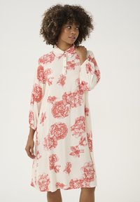 Rochie florală până la genunchi, de culoare crem, cu imprimeuri roșii de flori, având un guler, placket cu nasturi și mâneci bufante pentru un aspect texturat.