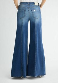 Laiad denim teksad keskmiselt sinises toonis, kõrge taljega, kahe tagataskuga ja puhtaäärisega. Kangas on sujuva tekstuuriga ja kerge pleekimisega.
