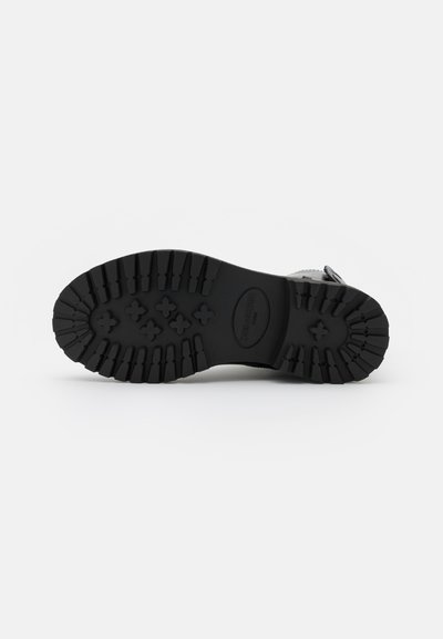 Black rubber sole with deep treads and textured surface; features a rounded toe and sturdy construction for durability and traction.