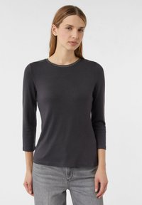 Dunkelgraues Langarm-T-Shirt mit rundem Ausschnitt und hellen Akzenten am Kragen, aus weichem Stoff mit glatter Textur, getragen mit grauen Jeans.