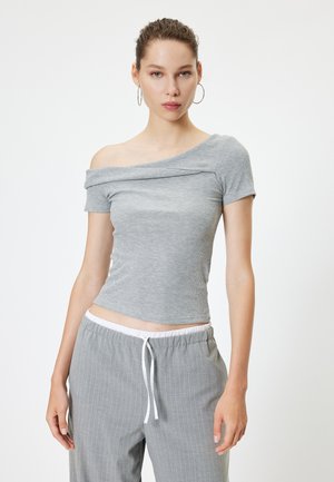 Top gris acanalado con hombros al descubierto y mangas cortas, con una silueta ajustada, combinado con pantalones de rayas gris claro que tienen una cintura elástica.