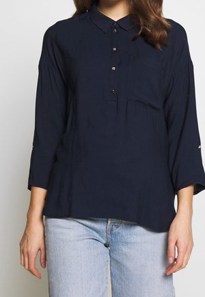 Marineblaue Hemdbluse mit Kragen, dreiviertel Ärmeln und Brusttasche. Aus weichem Stoff gefertigt und mit lockerem Schnitt.